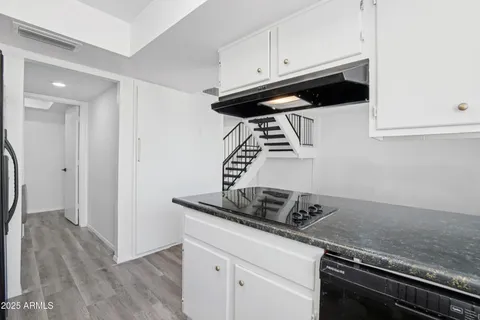 a kitchen with granite countertop a sink stainless steel appliances and white cabinets