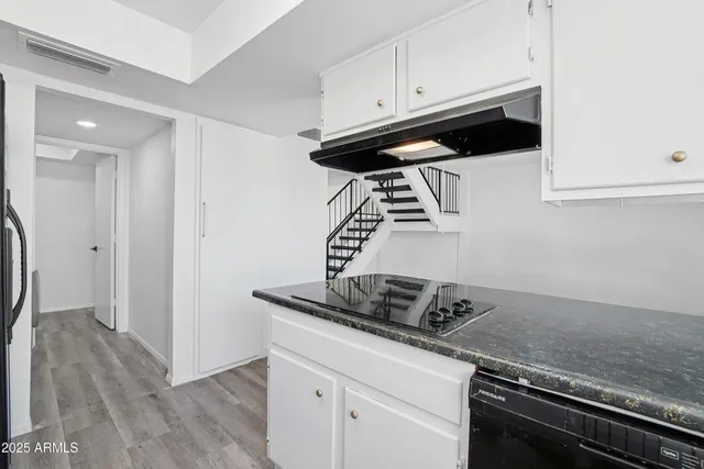 a kitchen with granite countertop a sink stainless steel appliances and white cabinets