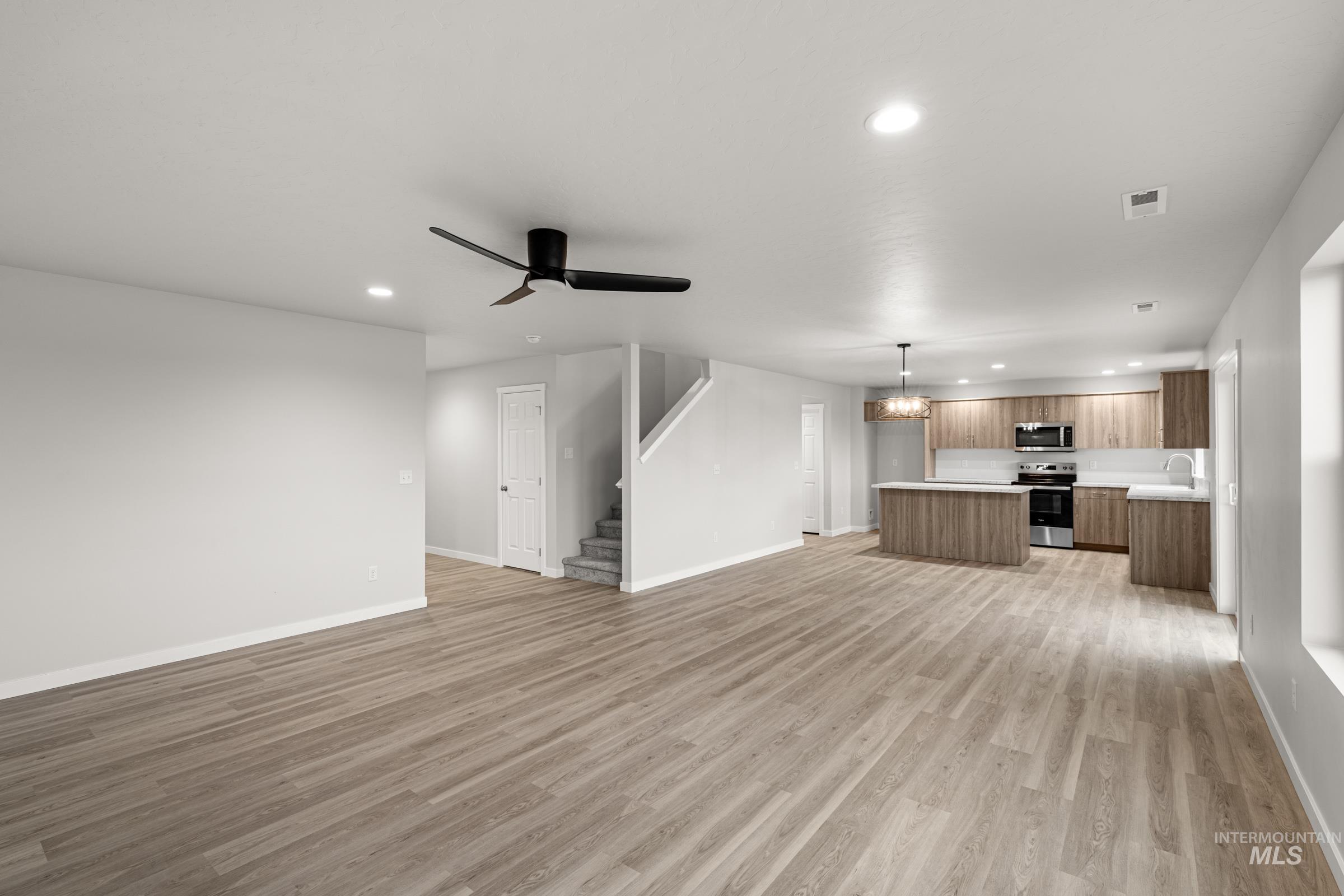 13693 Redway Court Caldwell, ID 83607 - Photo 9 of 25 Unfurnished living room featuring ceiling fan, hanging lights, and light wood-style flooring