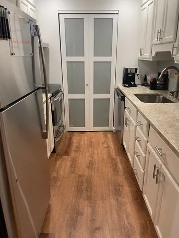 a kitchen with sink a refrigerator and wooden floor
