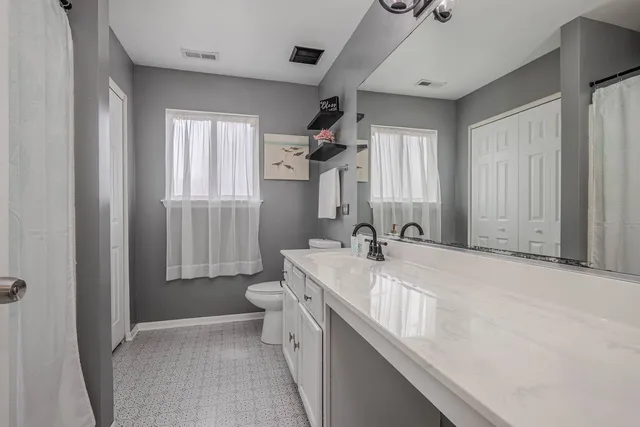 a bathroom with a granite countertop sink mirror vanity and toilet