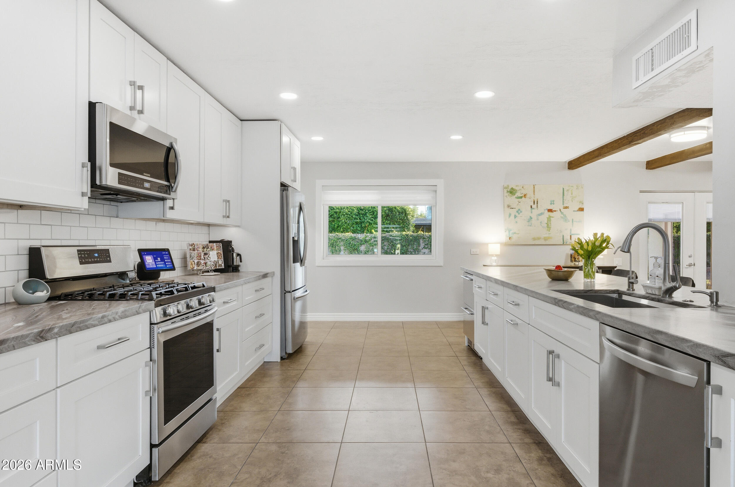 3541 East Cannon Drive Phoenix, AZ 85028 - Photo 3 of 42 a kitchen with stainless steel appliances granite countertop white cabinets a sink dishwasher and a stove top oven with wooden floor