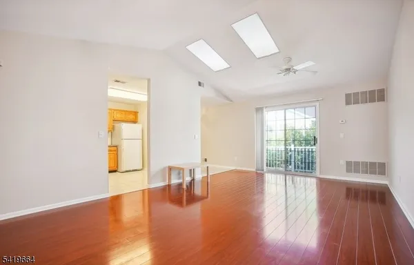 a view of an empty room with wooden floor and a window
