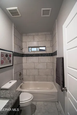 a bathroom with a granite countertop toilet a sink and bathtub