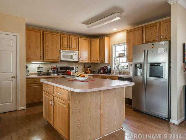6713 Potter Road Waxhaw, NC 28173 - Photo 6 of 16 a kitchen with stainless steel appliances granite countertop a refrigerator a sink a stove a washer and dryer with wooden floor