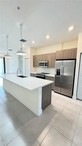 a large kitchen with kitchen island a sink a counter top space and cabinets