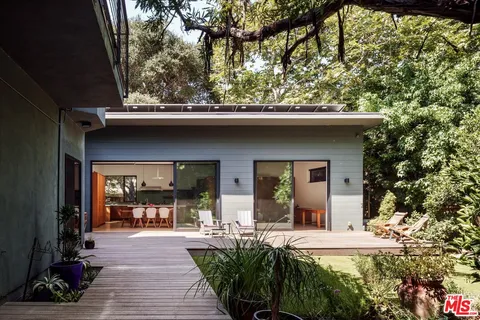 a view of a house with large trees and plants