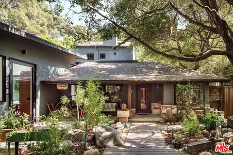 a view of a house with potted plants and large tree