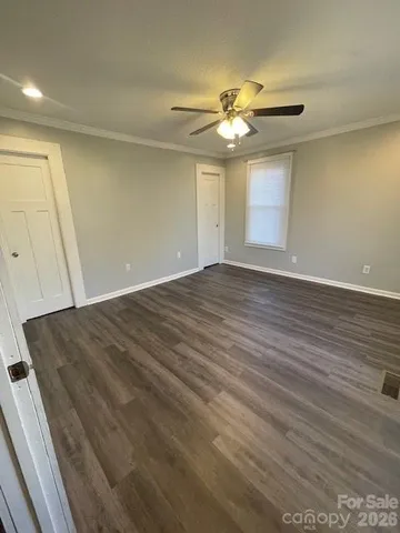 a view of an empty room with wooden floor and a ceiling fan