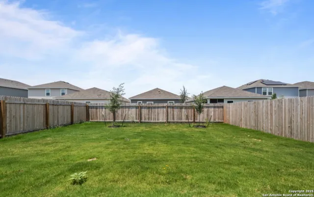 a view of a big house with a yard and wooden fence