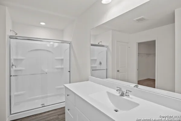 a bathroom with a shower sink vanity and a mirror