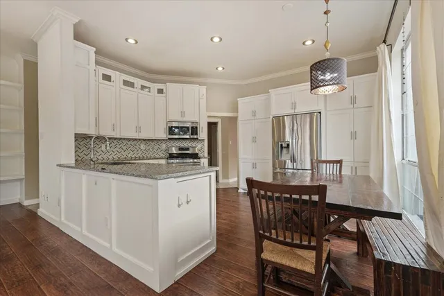 a kitchen with stainless steel appliances granite countertop a kitchen island hardwood floor and a sink
