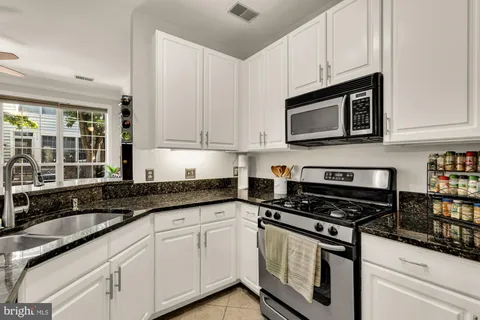 a kitchen with granite countertop white cabinets and black appliances