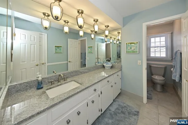a spacious bathroom with a granite countertop sink a toilet and a mirror