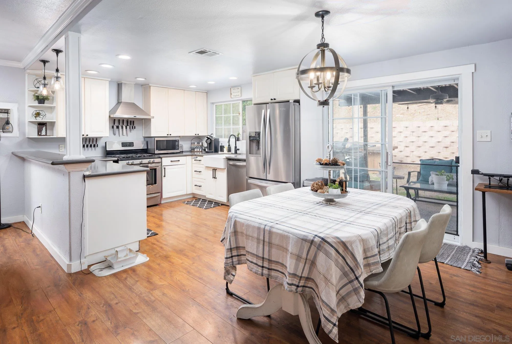 9357 Dempster Drive Santee, CA 92071 - Photo 11 of 35 a kitchen with granite countertop a stove a sink dishwasher a dining table and chairs with wooden floor