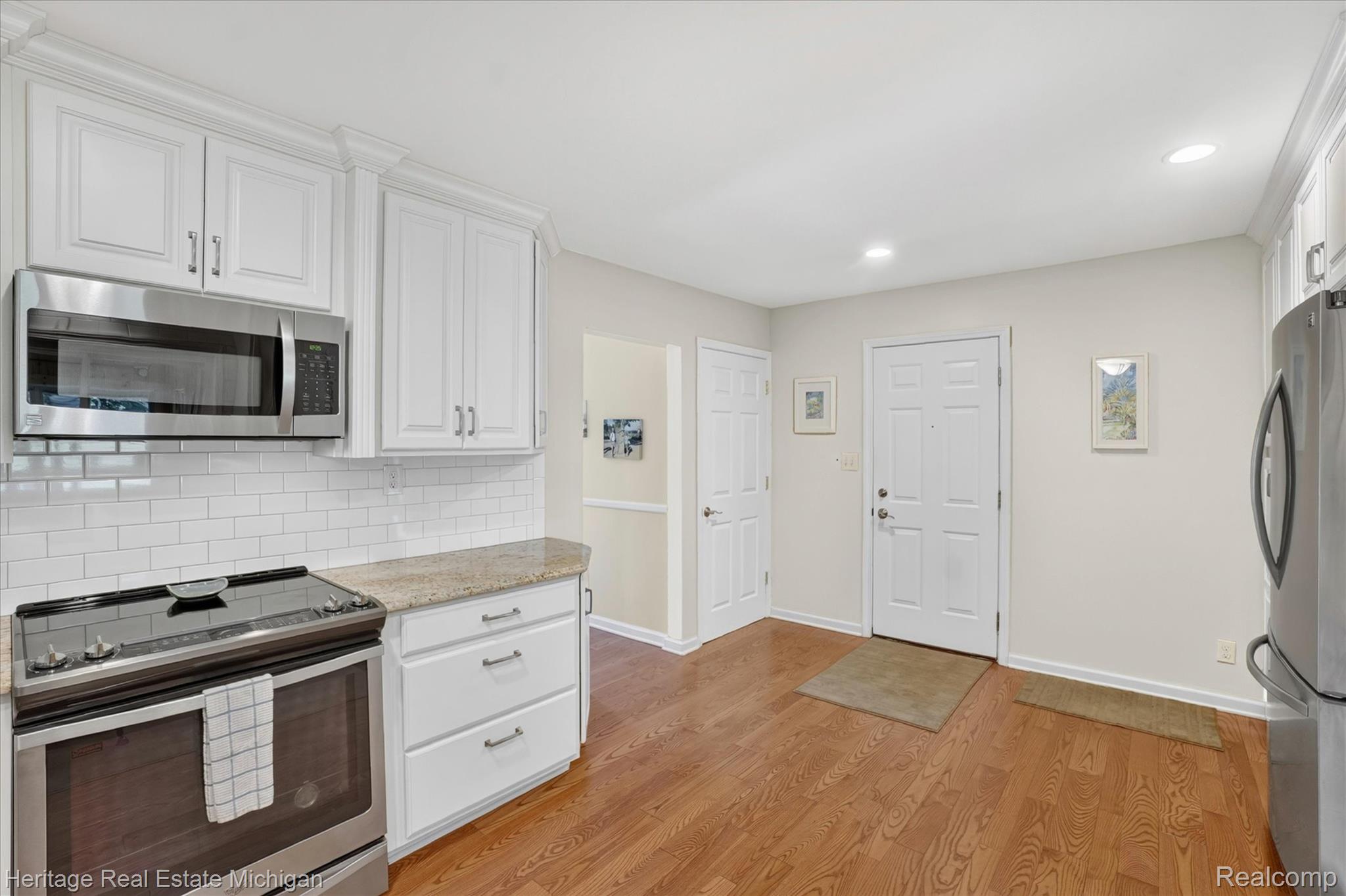 14038 North Hogan Road Linden, MI 48451 - Photo 18 of 53 Kitchen area featuring white cabinetry, stainless steel appliances, granite countertops, and subway tile backsplash