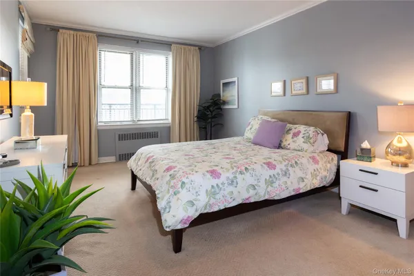 a bedroom with a bed lamp and a large window with garden view