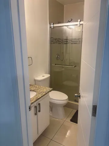 a bathroom with a granite countertop toilet and a sink