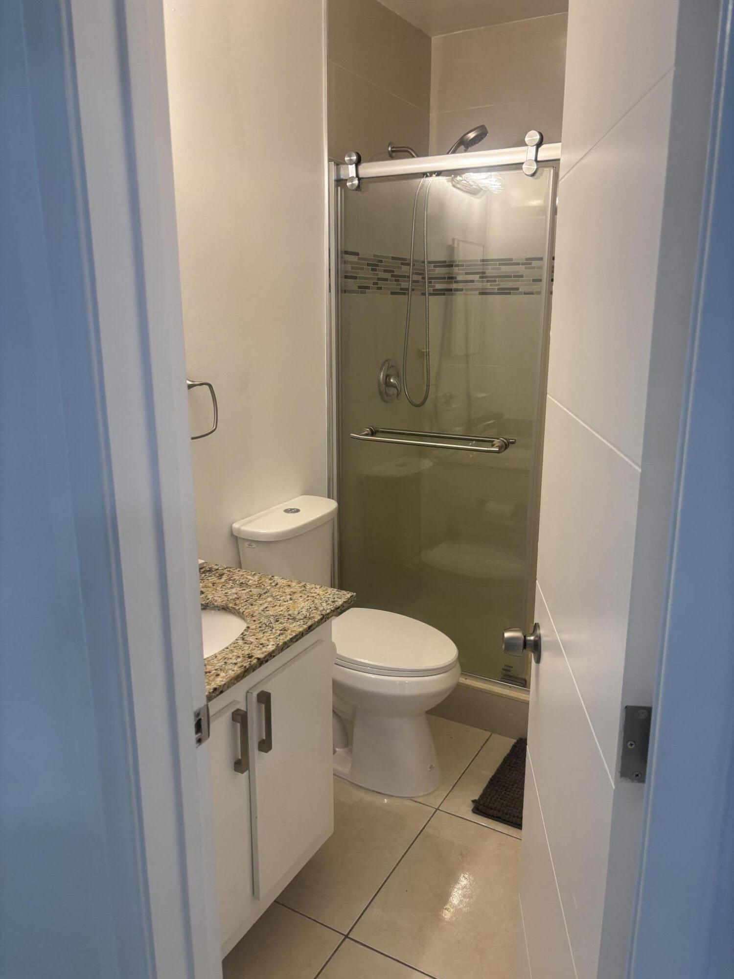 299 Southwest 7th Street, Unit 110 Boca Raton, FL 33432 - Photo 13 of 24 a bathroom with a granite countertop toilet and a sink