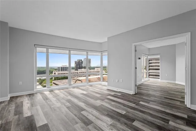an empty room with wooden floor and windows