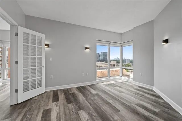 a view of empty room with wooden floor and a window