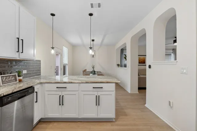 a kitchen with kitchen island granite countertop a sink a counter space appliances and cabinets