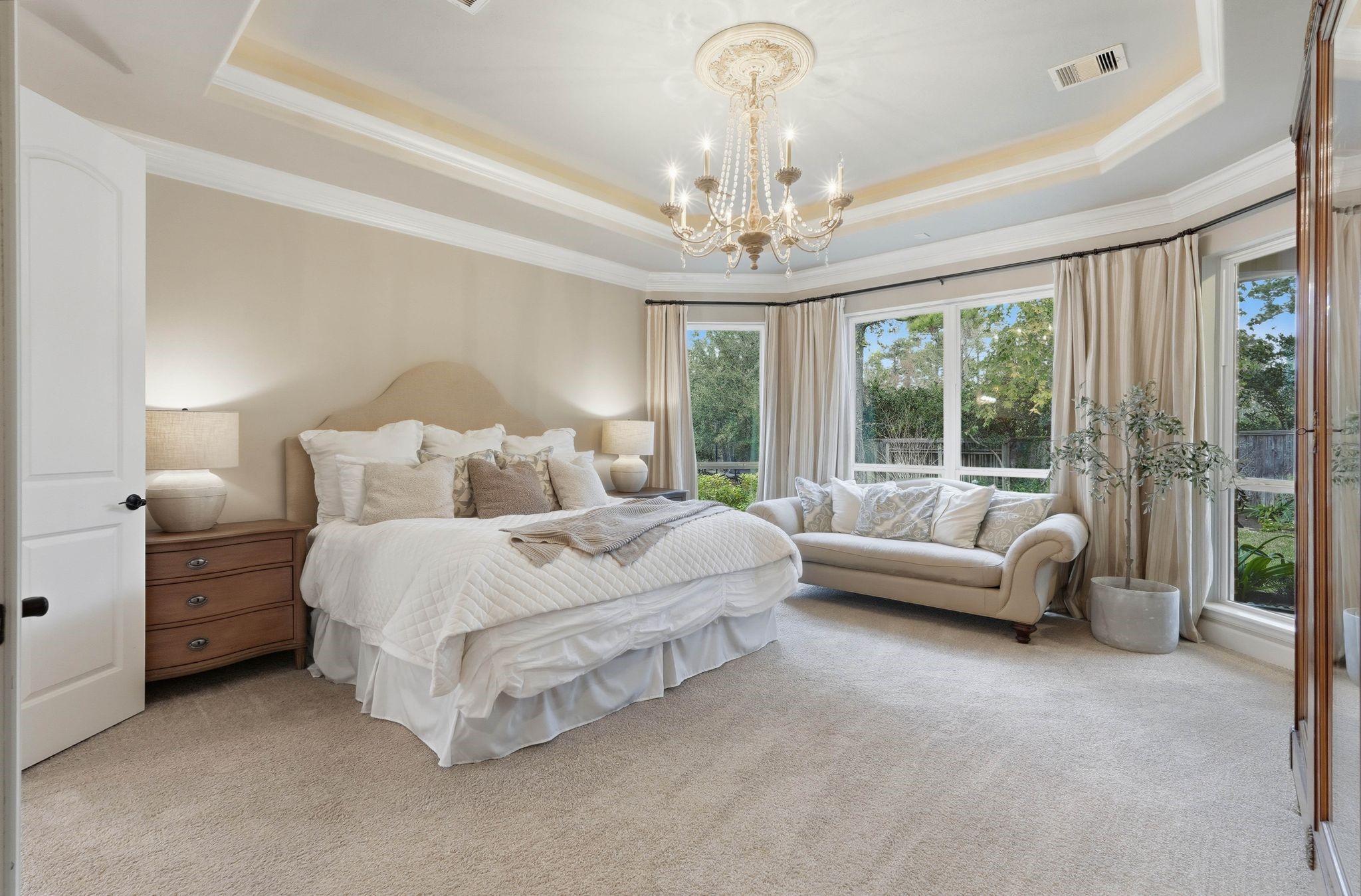 147 West Valera Ridge Place The Woodlands, TX 77389 - Photo 21 of 50 Light-filled primary suite offering a tray ceiling, beautiful chandelier, cozy sitting area, and peaceful backyard views.
