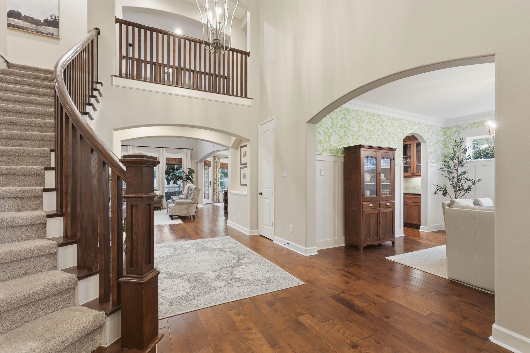 147 West Valera Ridge Place The Woodlands, TX 77389 - Photo 25 of 50 Heading upstairs in the two-story foyer with curved staircase, arched entryways, and hardwood floors.