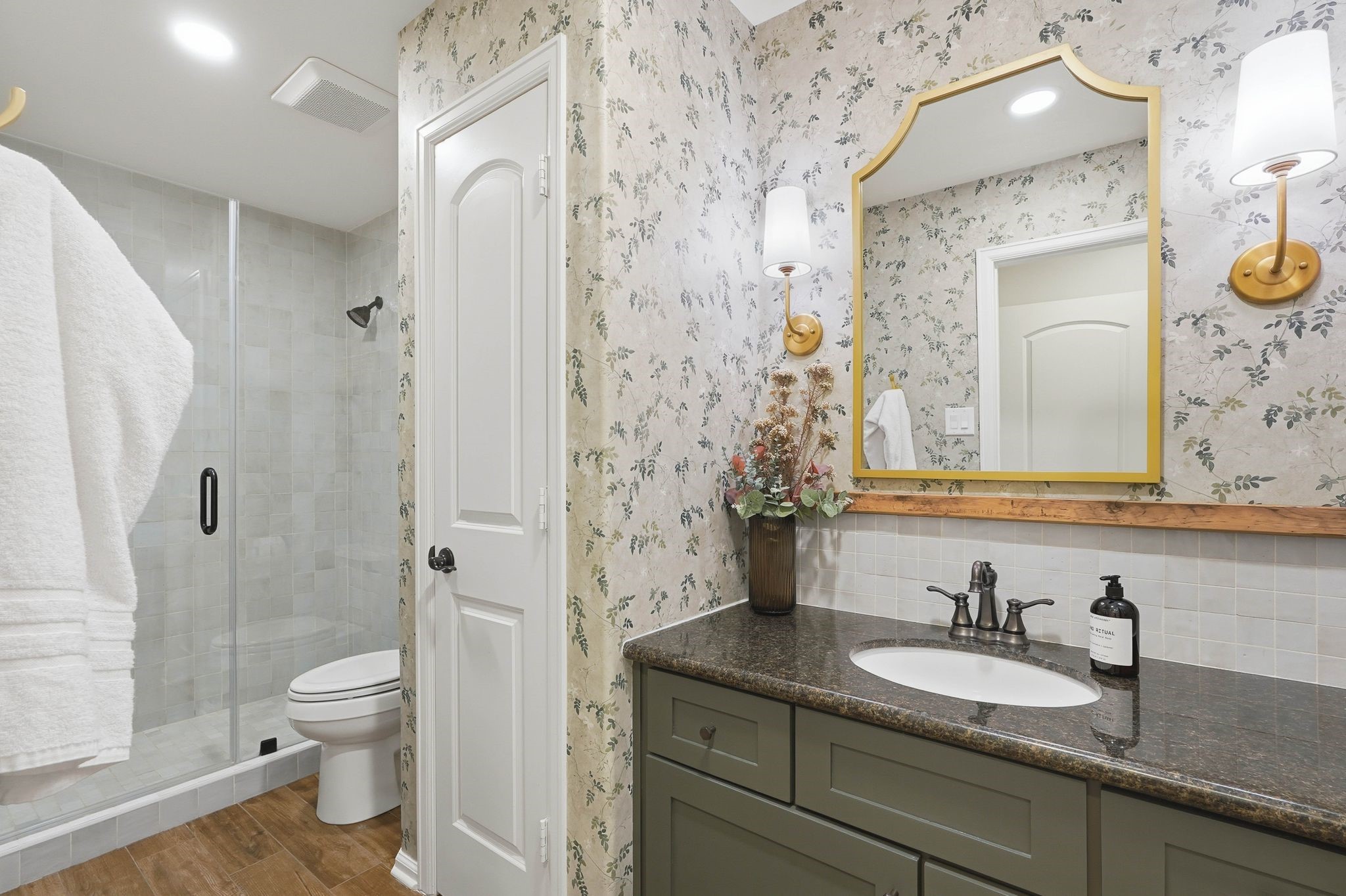 147 West Valera Ridge Place The Woodlands, TX 77389 - Photo 28 of 50 Stylish ensuite guest bath with custom wallpaper, tiled shower, coordinating tile backsplash at the vanity, granite countertop, and updated fixtures.