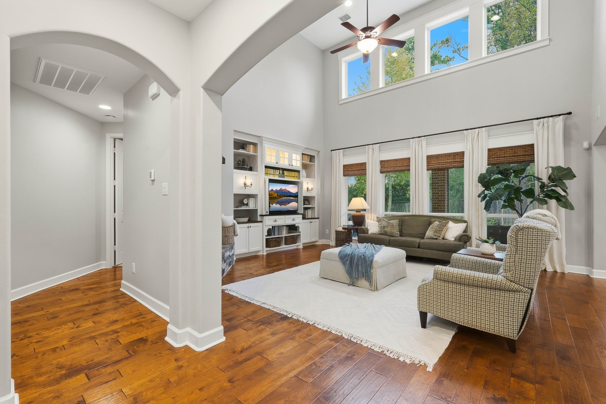 147 West Valera Ridge Place The Woodlands, TX 77389 - Photo 10 of 50 Grand living space with dramatic ceilings, arched architecture, custom built-ins, and abundant natural light. The left hallway offers seamless access to the primary suite, mudroom, laundry room, and garage.