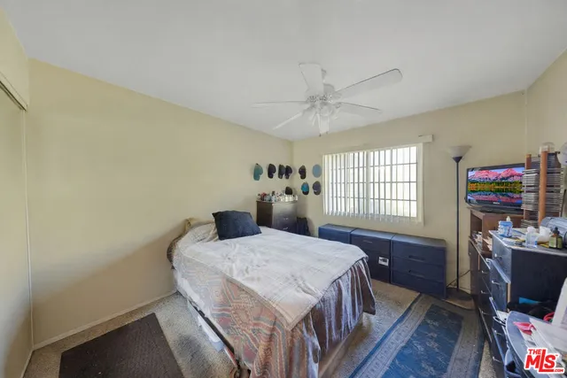 a bedroom with a bed a large window with wooden floor