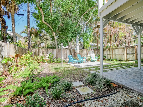 a view of a yard with plants and large trees