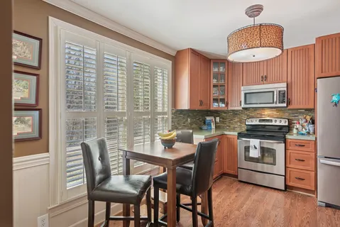 a kitchen with stainless steel appliances a dining table chairs and a wooden floor