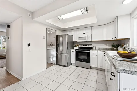 a kitchen with granite countertop a refrigerator oven a sink and cabinets