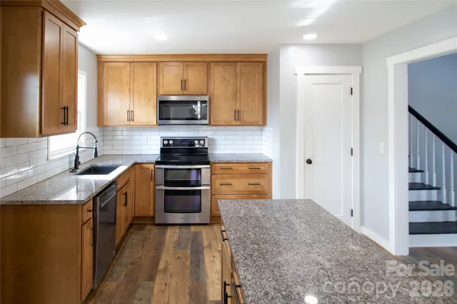 a kitchen with stainless steel appliances granite countertop a stove top oven a sink and a granite counter tops