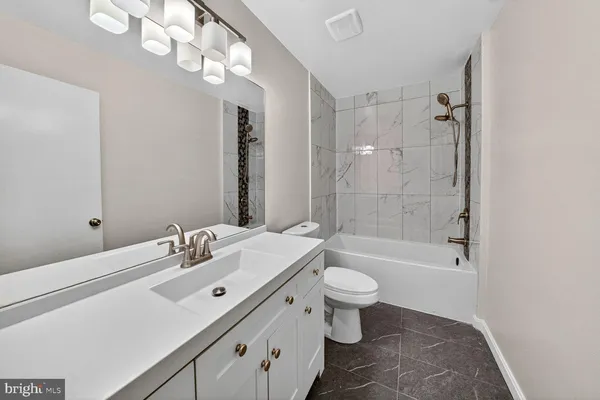 a bathroom with a bathtub shower sink mirror vanity and toilet