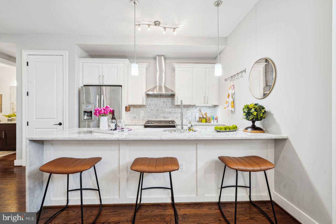 1401 K Street Southeast, Unit 1 Washington, DC 20003 - Photo 13 of 48 a kitchen with stainless steel appliances a dining table chairs refrigerator and cabinets