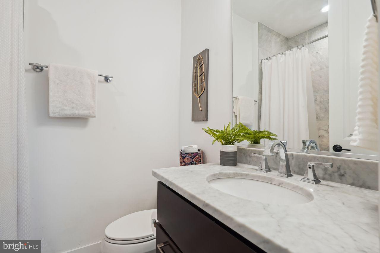 1401 K Street Southeast, Unit 1 Washington, DC 20003 - Photo 35 of 48 a bathroom with a granite countertop sink a toilet and mirror