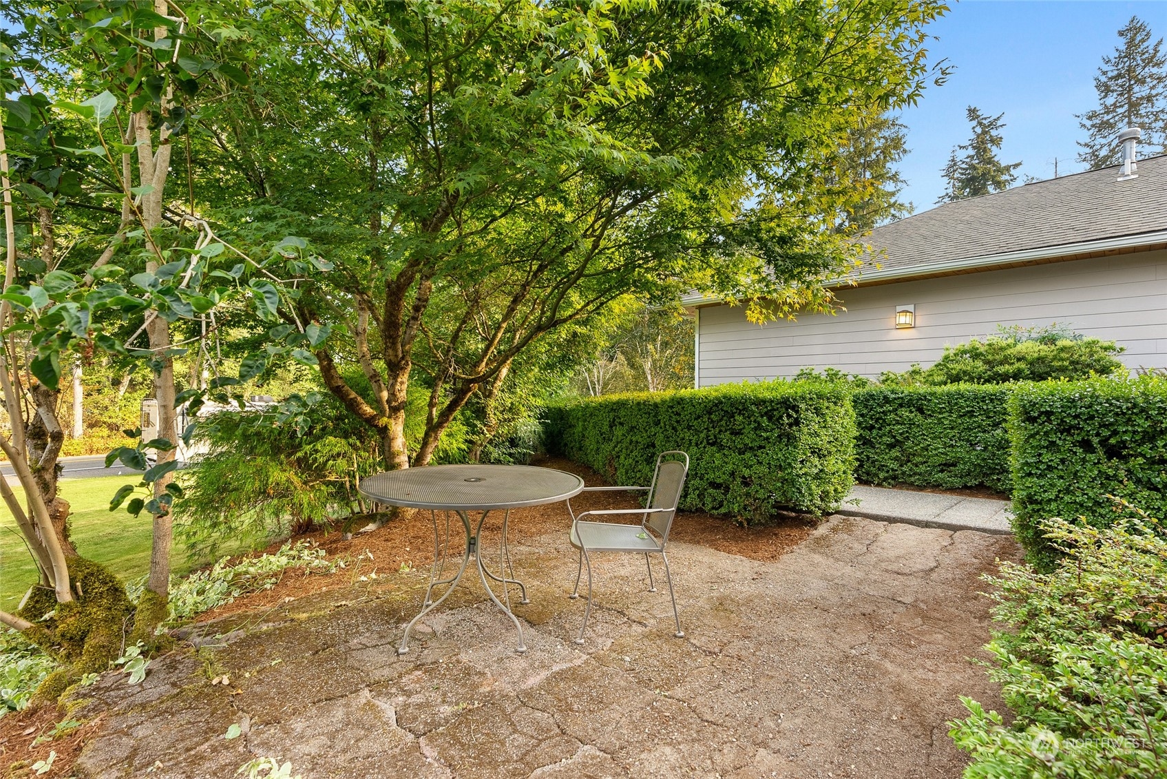 17310 Freestad Road Arlington, WA 98223 - Photo 22 of 29 a view of a backyard with plants and a lawn chair under an umbrella