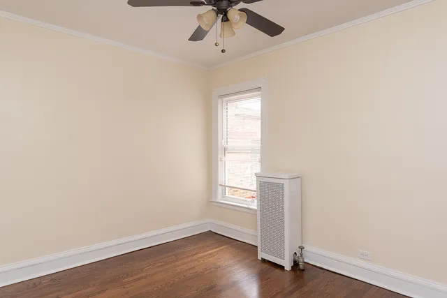 an empty room with wooden floor chandelier fan and windows