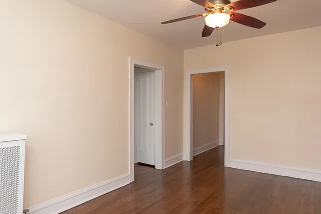 an empty room with wooden floor fan and windows