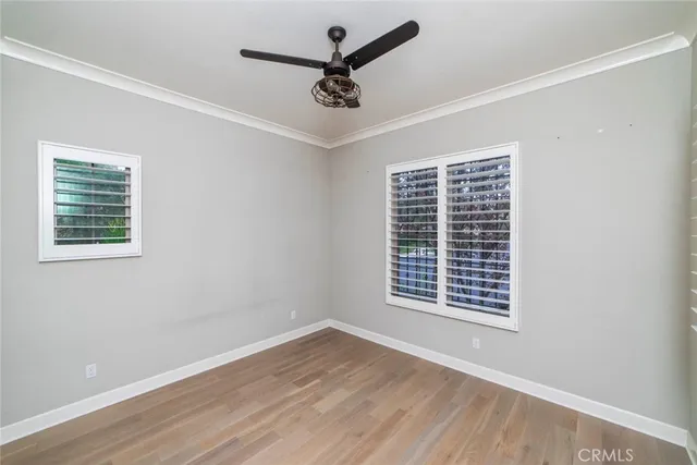 a view of empty room with wooden floor and fan