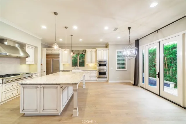 a large kitchen with kitchen island a large counter top a stove a sink and a chandelier
