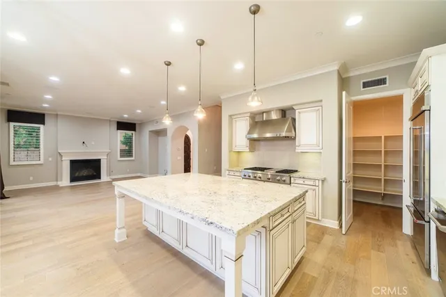 a large kitchen with kitchen island a stove a sink a oven and a fireplace with wooden floor