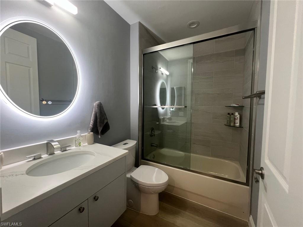 817 Regency Reserve Circle, Unit 3901 Naples, FL 34119 - Photo 18 of 35 Full bathroom with shower / bath combination with glass door, wood-type flooring, vanity, and toilet