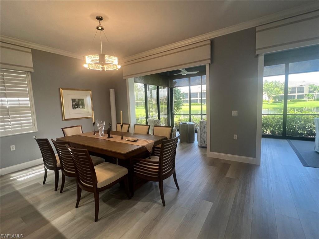 817 Regency Reserve Circle, Unit 3901 Naples, FL 34119 - Photo 4 of 35 Dining room with a notable chandelier, ornamental molding, a healthy amount of sunlight, and hardwood / wood-style floors