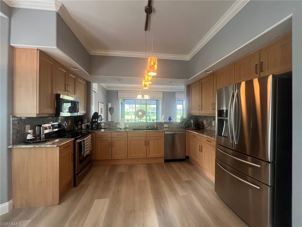 817 Regency Reserve Circle, Unit 3901 Naples, FL 34119 - Photo 5 of 35 Kitchen with light hardwood / wood-style floors, kitchen peninsula, stainless steel appliances, backsplash, and sink