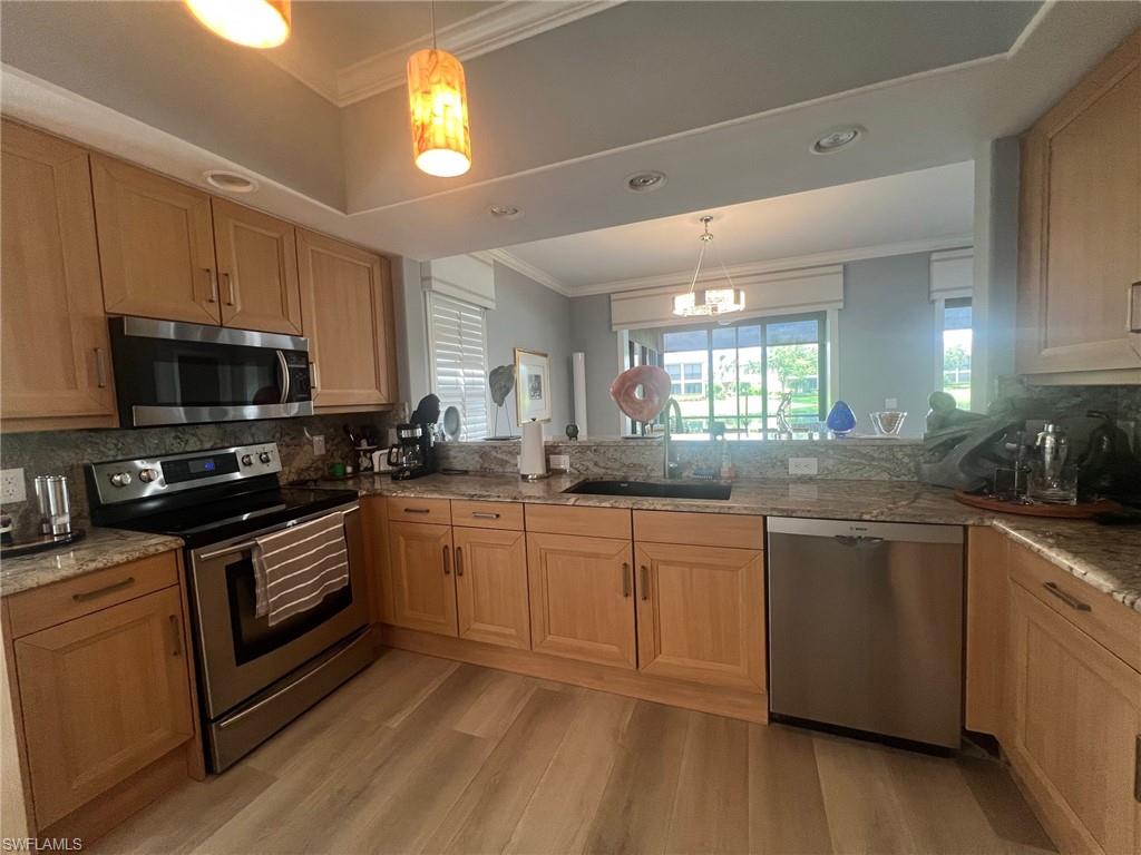 817 Regency Reserve Circle, Unit 3901 Naples, FL 34119 - Photo 6 of 35 Kitchen with backsplash, appliances with stainless steel finishes, sink, and light hardwood / wood-style flooring