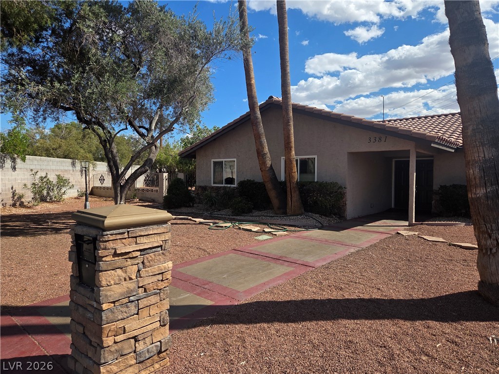 3381 Westwind Road Las Vegas, NV 89146 - Photo 4 of 52 A terracotta-tiled roof crowns this charming desert home, framed by mature trees and a neatly graveled yard.
