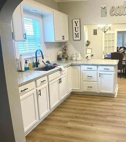 a kitchen with granite countertop white cabinets white appliances a sink and a window